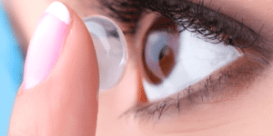 Person holding contact lenses with a red stop sign overlay.